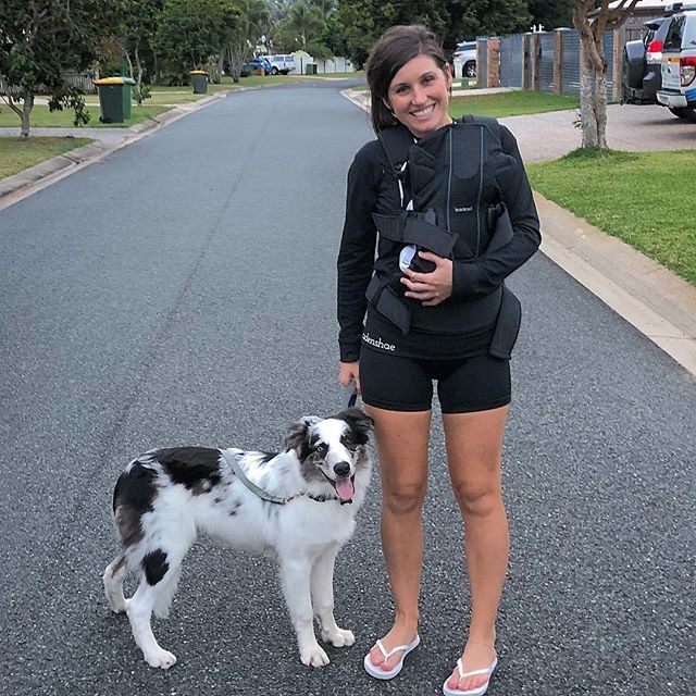 Active mum in SRC pregnancy shorts, carrying her baby in a carrier, while walking the dog in the neighbourhood.