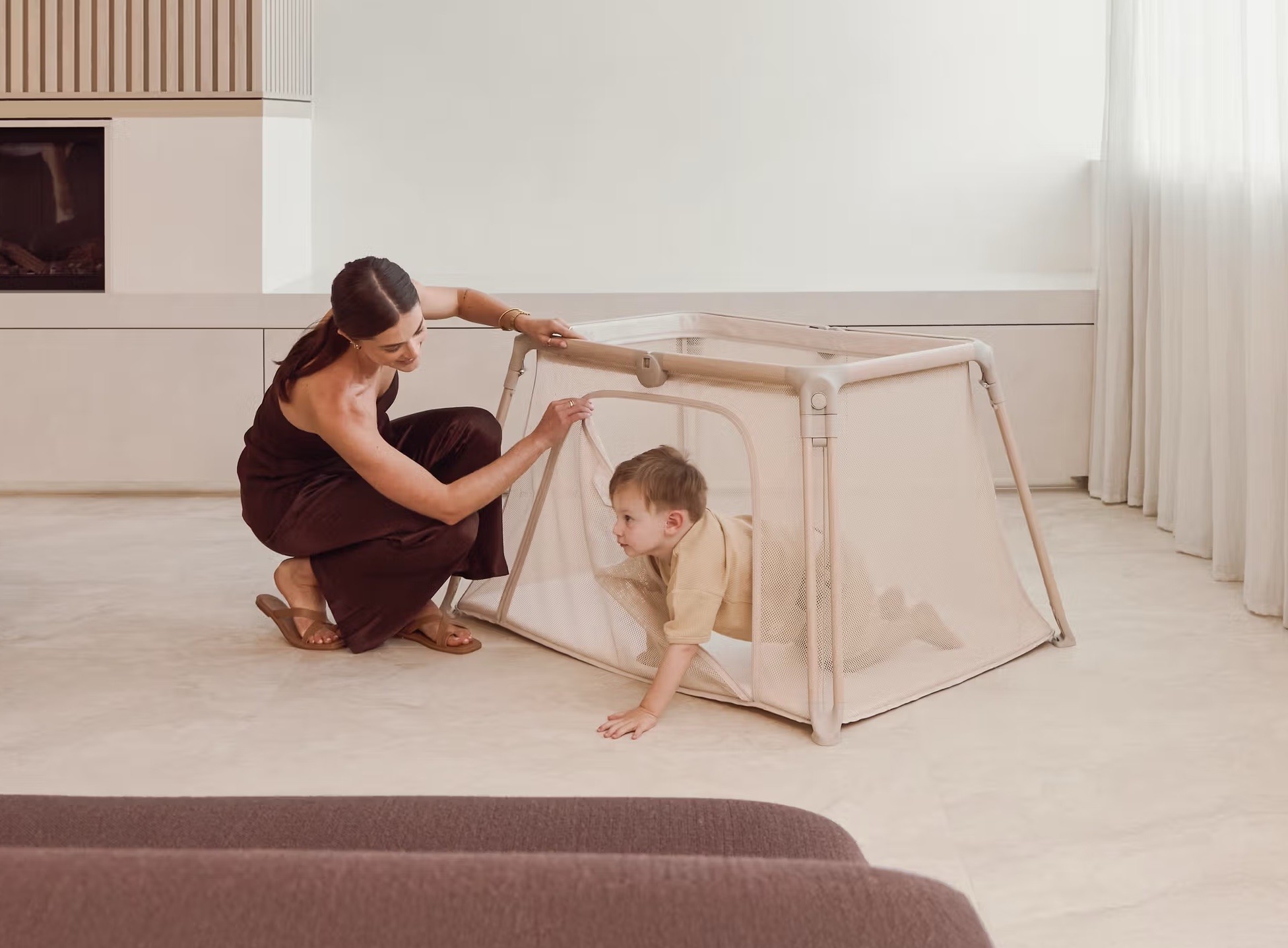 The Redsbaby VOYA portacot, shown with a toddler crawling out of the side zip section