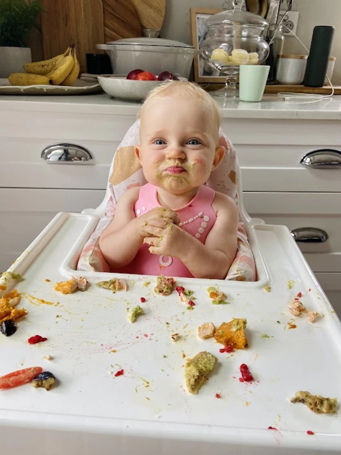 Joyful baby enjoying first solids at a messy table, demonstrating practical tips for introducing solids to baby.