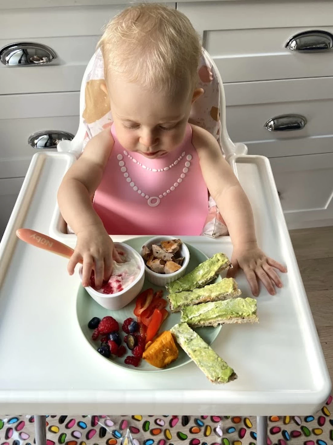 Smiling baby enjoying solid food, demonstrating practical steps for introducing solids to baby.