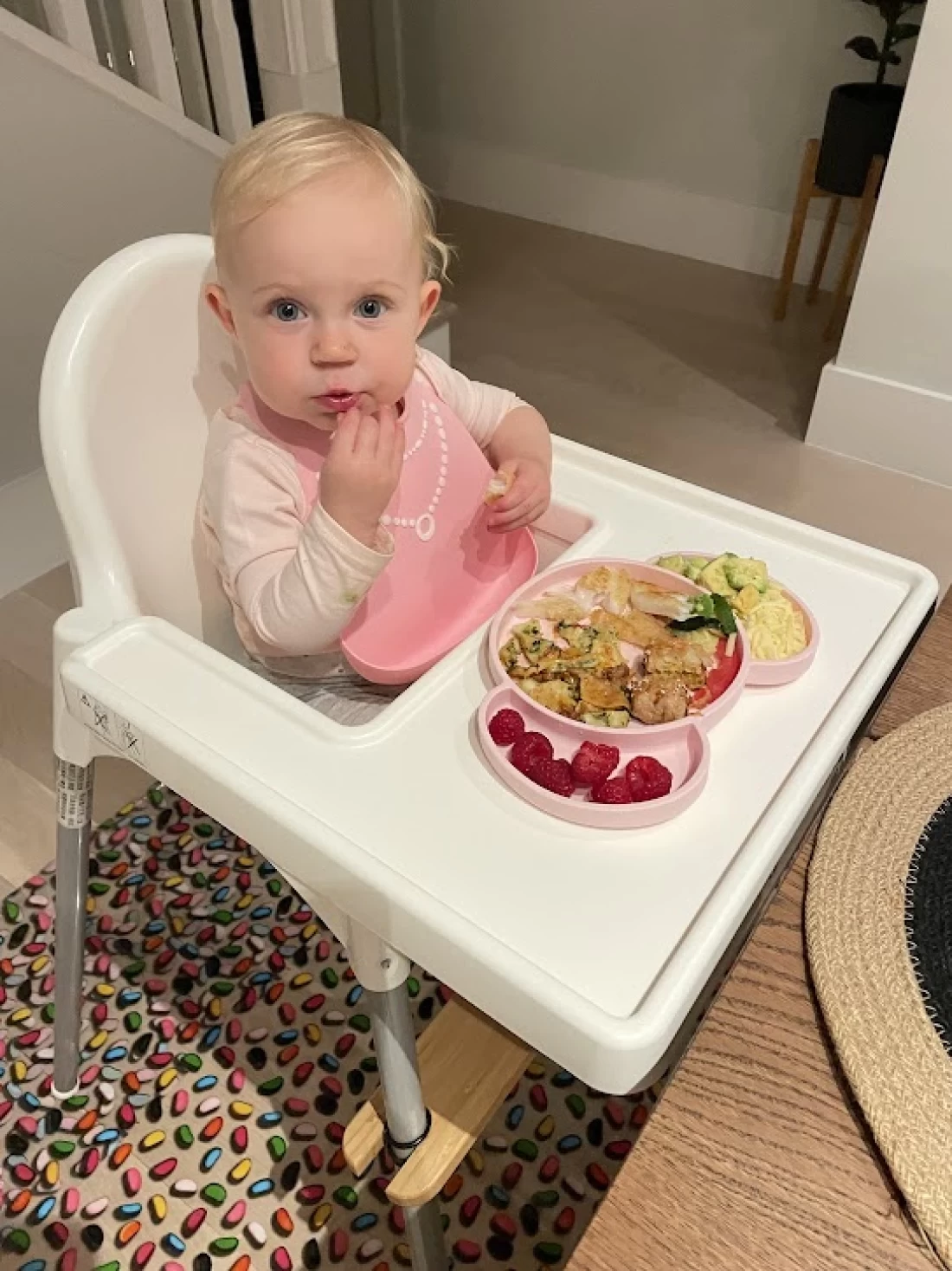 Close-up of a baby on a booster seat enjoying first solid foods, illustrating introducing solids to baby.