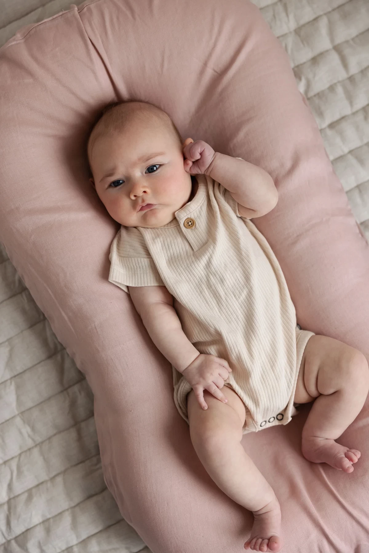 The Linen Label baby lounger in Australia, shown in pink with a baby on it