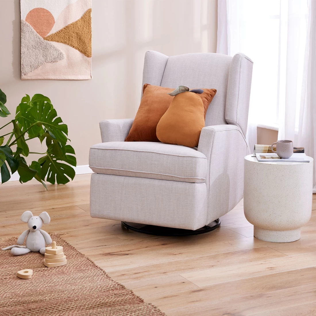 Chelsea Glider Recliner Nursery Chair in Egg Shell styled with two orange pillows in a cosy nursery room.