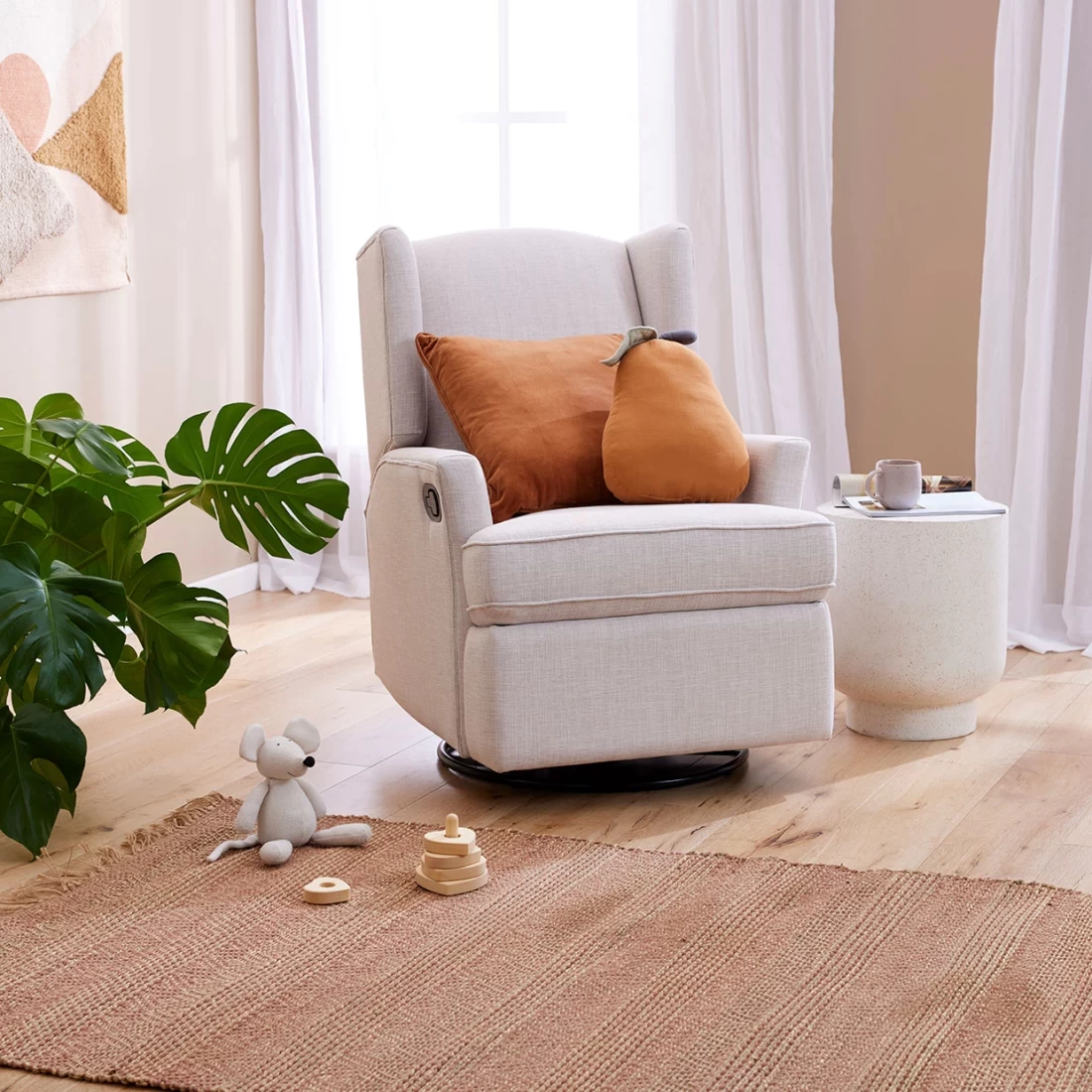 Modern nursery room featuring the Chelsea Glider Recliner Nursery Chair in Egg Shell with two orange accent pillows.
