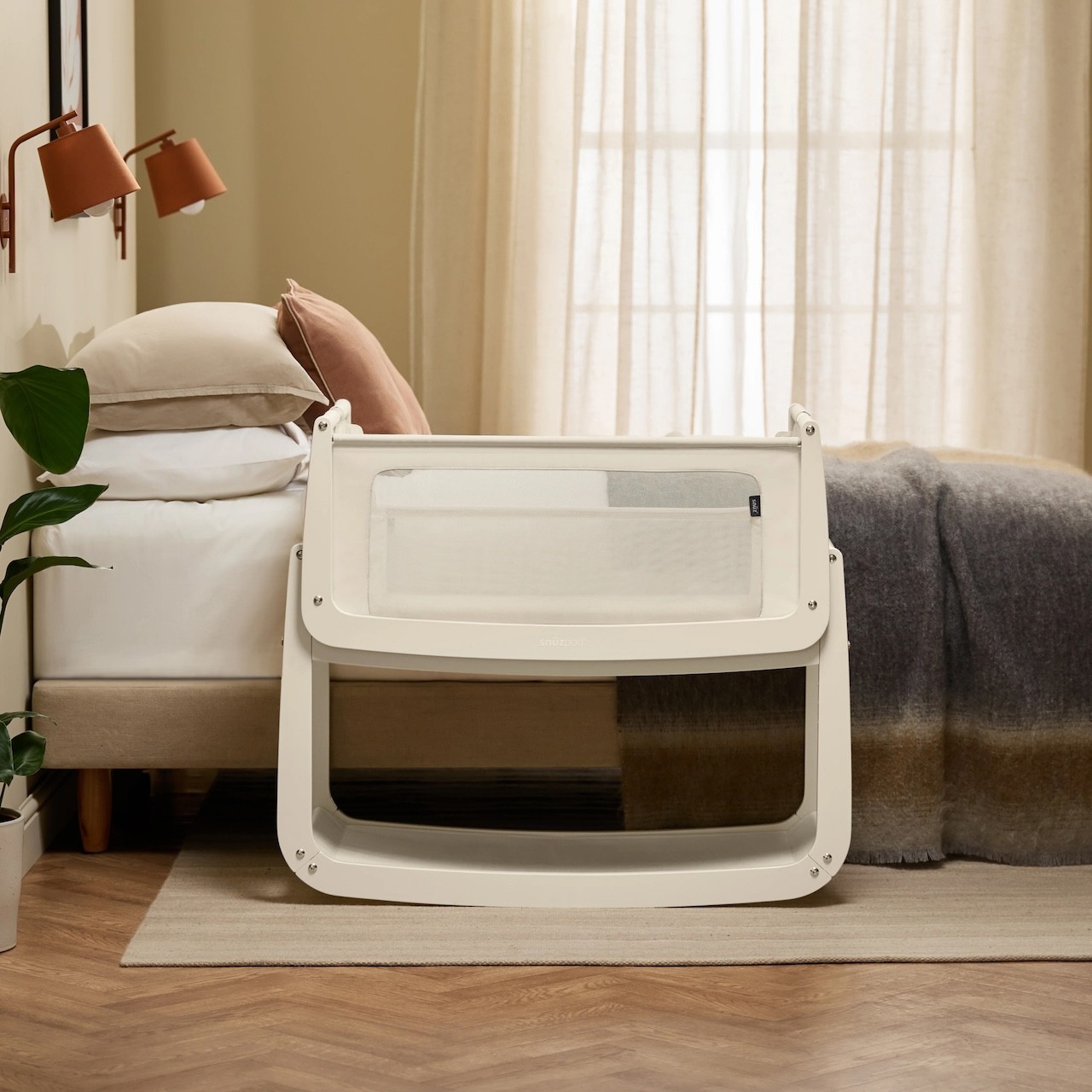 The Snuzpod baby bassinet cosleeper sitting next to a bed