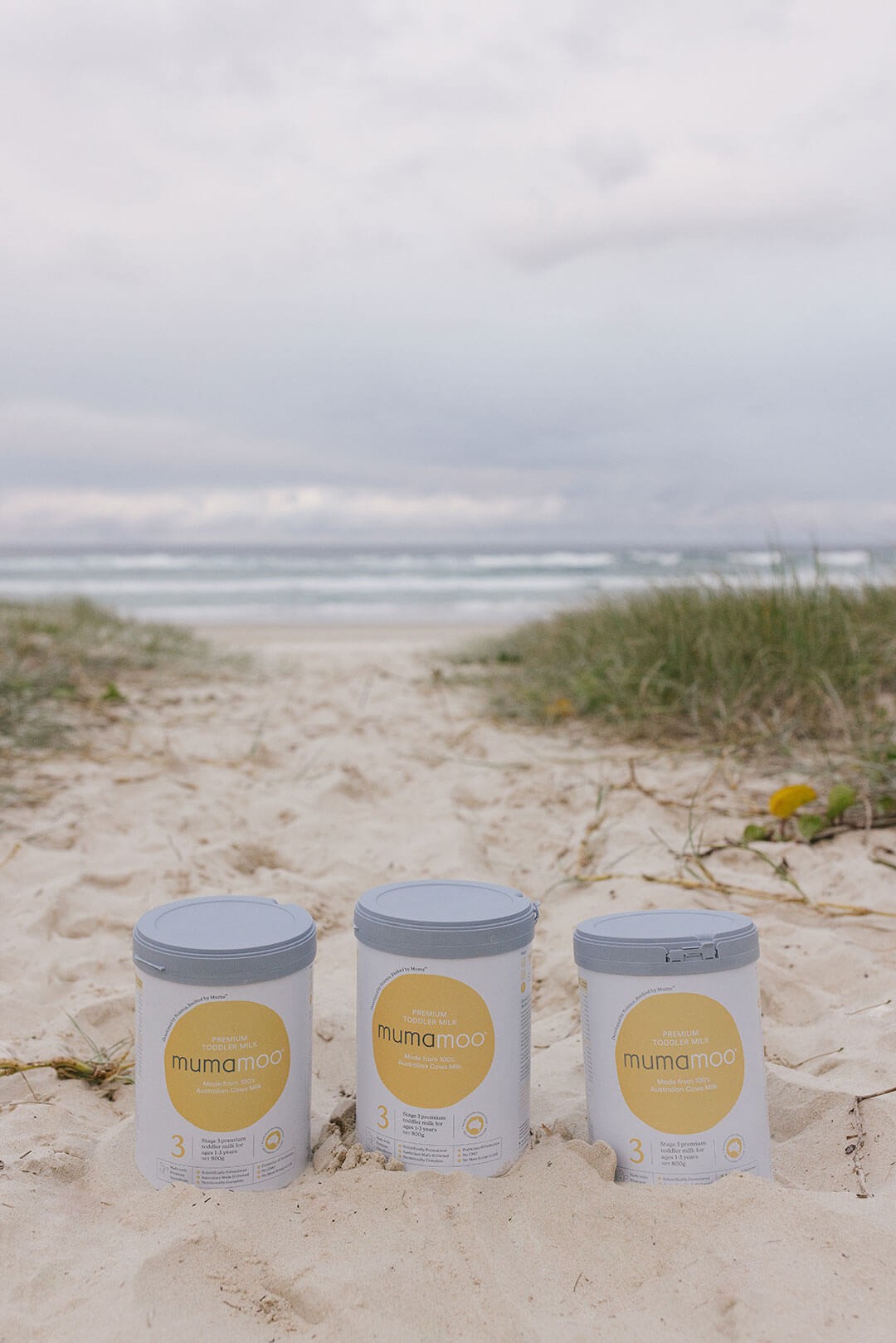 Three bottles of toddler formula from mumamoo placed on beach sand - rated #1 in Australia