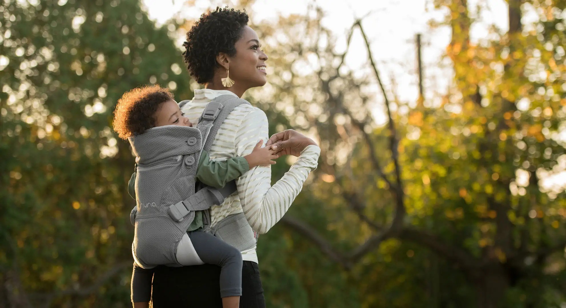 A mum showing how you can carry the Nuna Cudl on your back