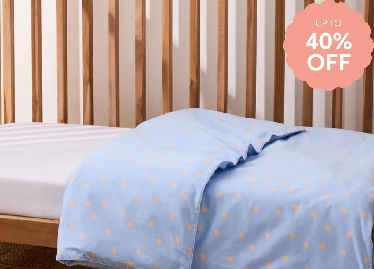 a baby cot with spotted sheets