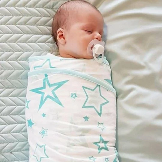 A sleeping baby wrapped in a miracle blanket swaddle