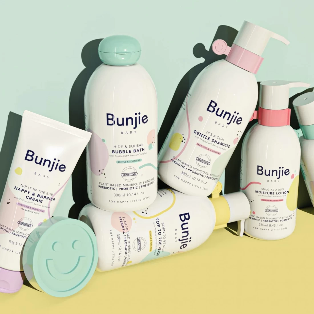 Six varieties of Bunjie Baby Skincare on yellow and mint green background – best eczema cream for babies with gentle natural formulas