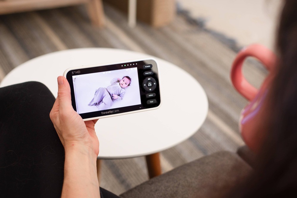 Mum watching baby on phone using Tweetycam – the best baby monitor for remote viewing and peace of mind.