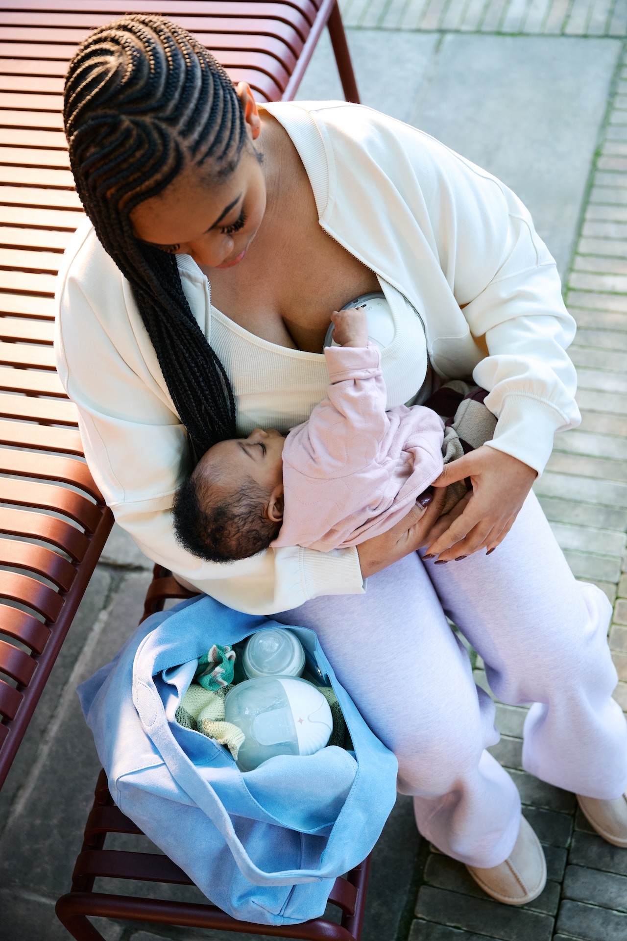A mum rocking her baby while wearing the Tommee Tippee Wearable Breast Pump