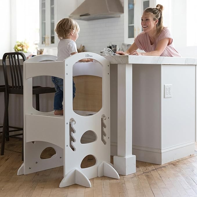 A toddler spending time with their mum in a little partners learning tower in the kitchen