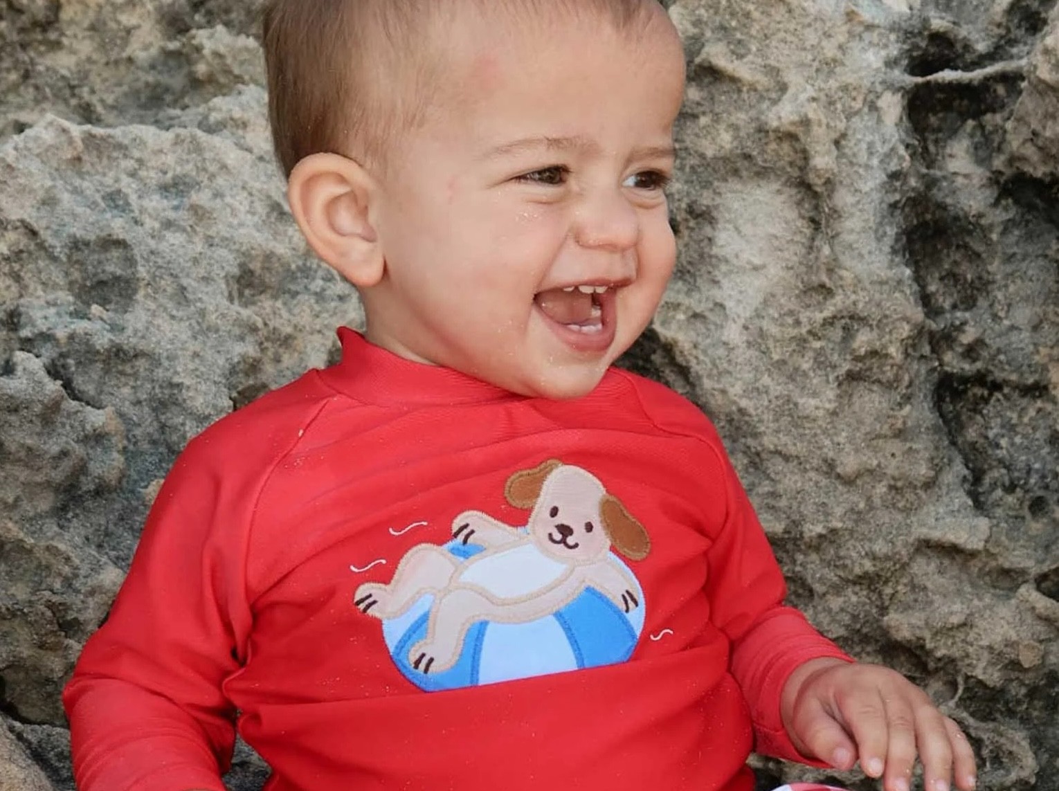 A baby in a red swimsuit by a baby swimwear brand