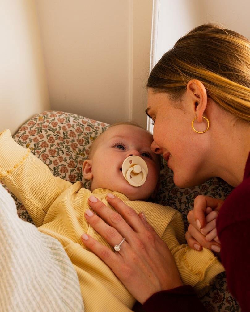 A mother playing with her newborn baby who is using the BIBs baby dummies.