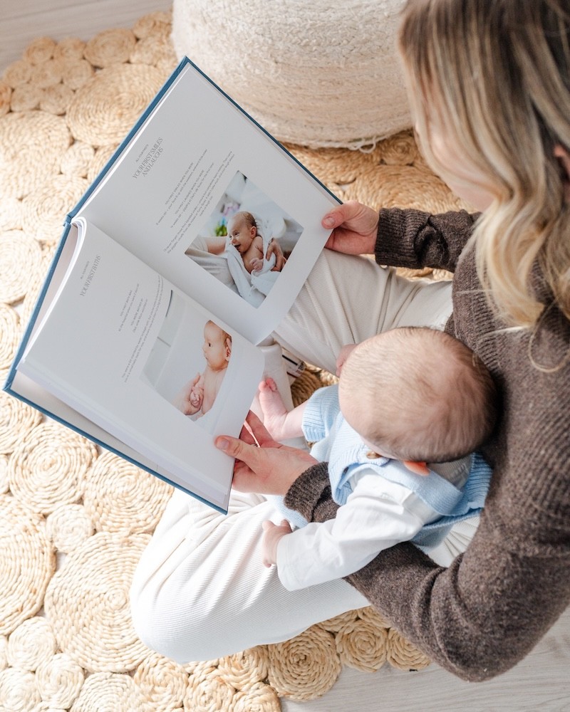 a mum showing her baby her new mum gift, a baby book