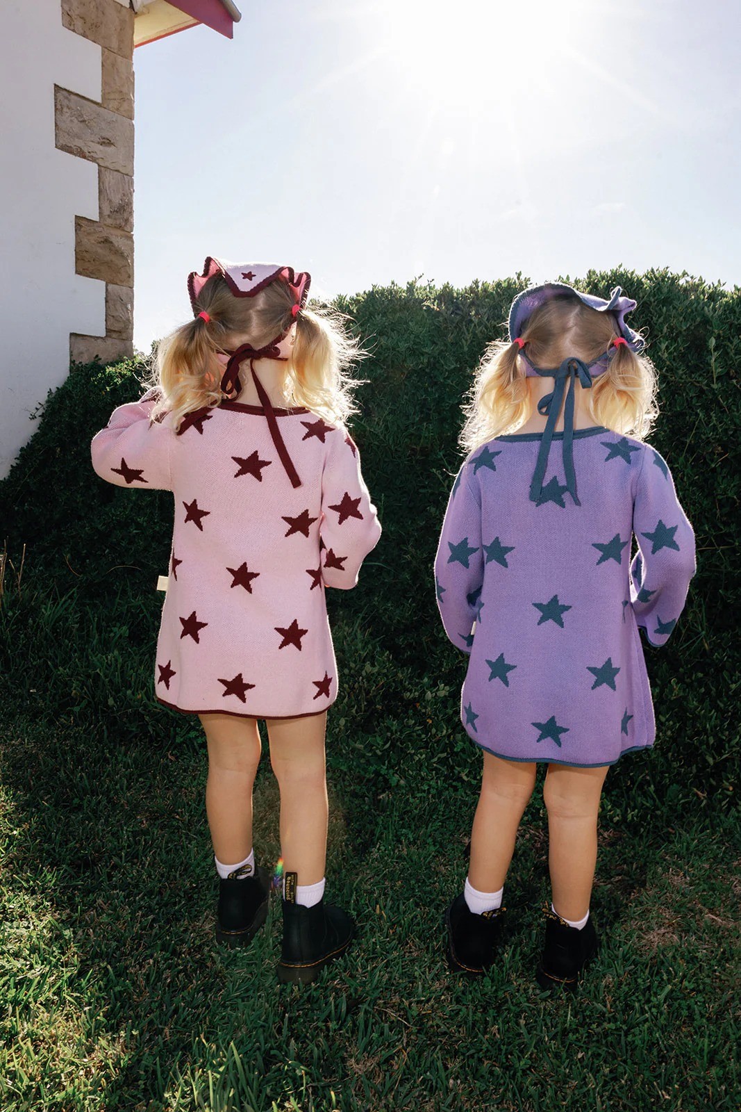Two little girls standing facing away from the camera wearing dresses with stars on them