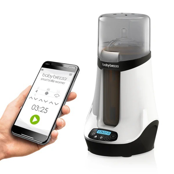 The baby brezza bottle warmer with a person holding a phone with the app open, showing its technology