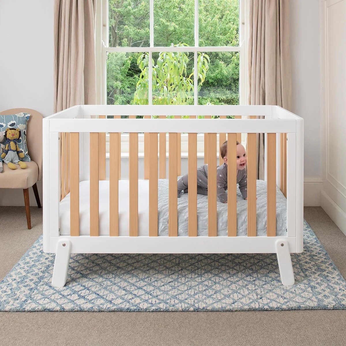 A baby in the Boori Turin Compact Baby cot in a nursery