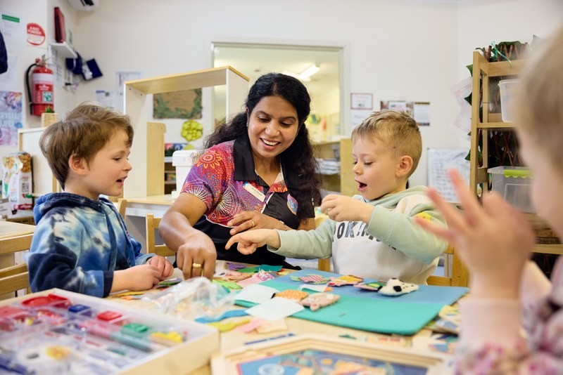 Teacher from the best childcare and daycare centre guiding toddlers in a fun learning activity.
