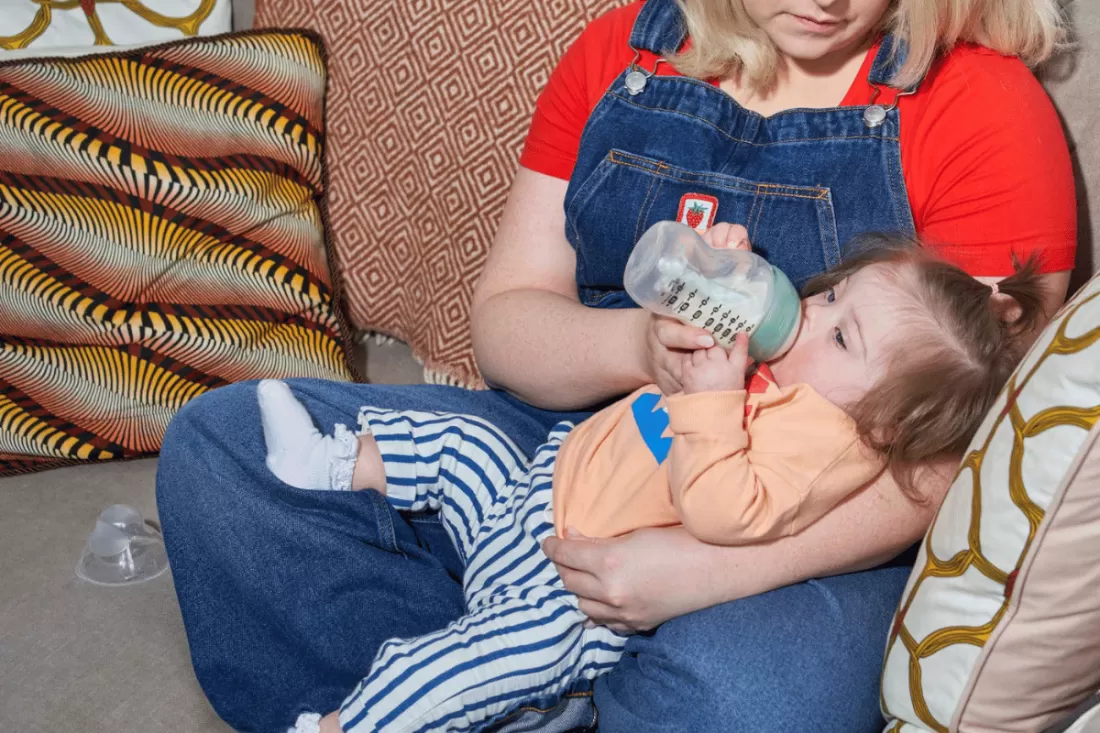 Mum feeding her baby with Tommee Tippee bottle as baby sleeps – a convenient solution for restful nights.