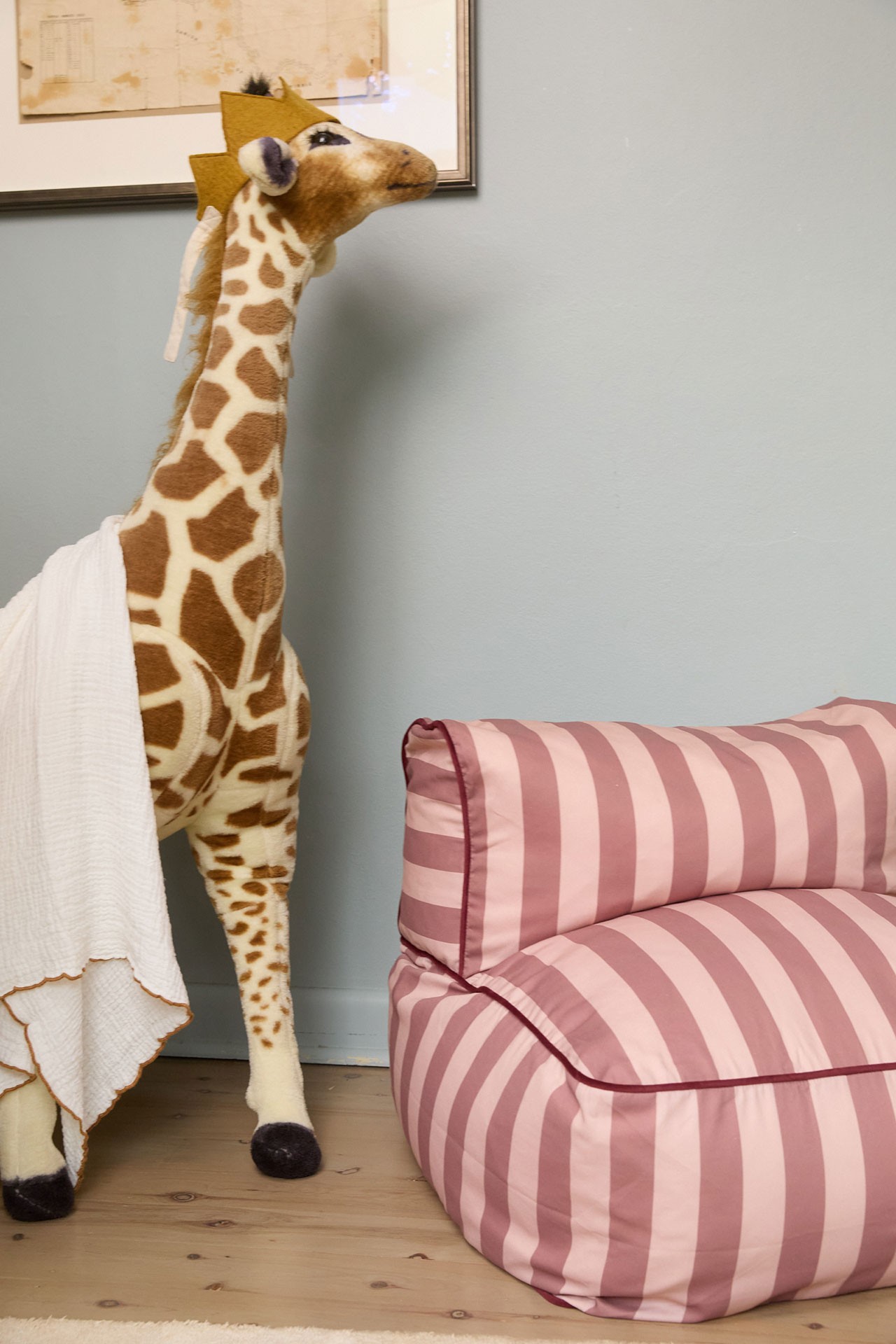 Adorable toddler lounge in pink and white stripes next to a toy giraffe, perfect for cosy reading