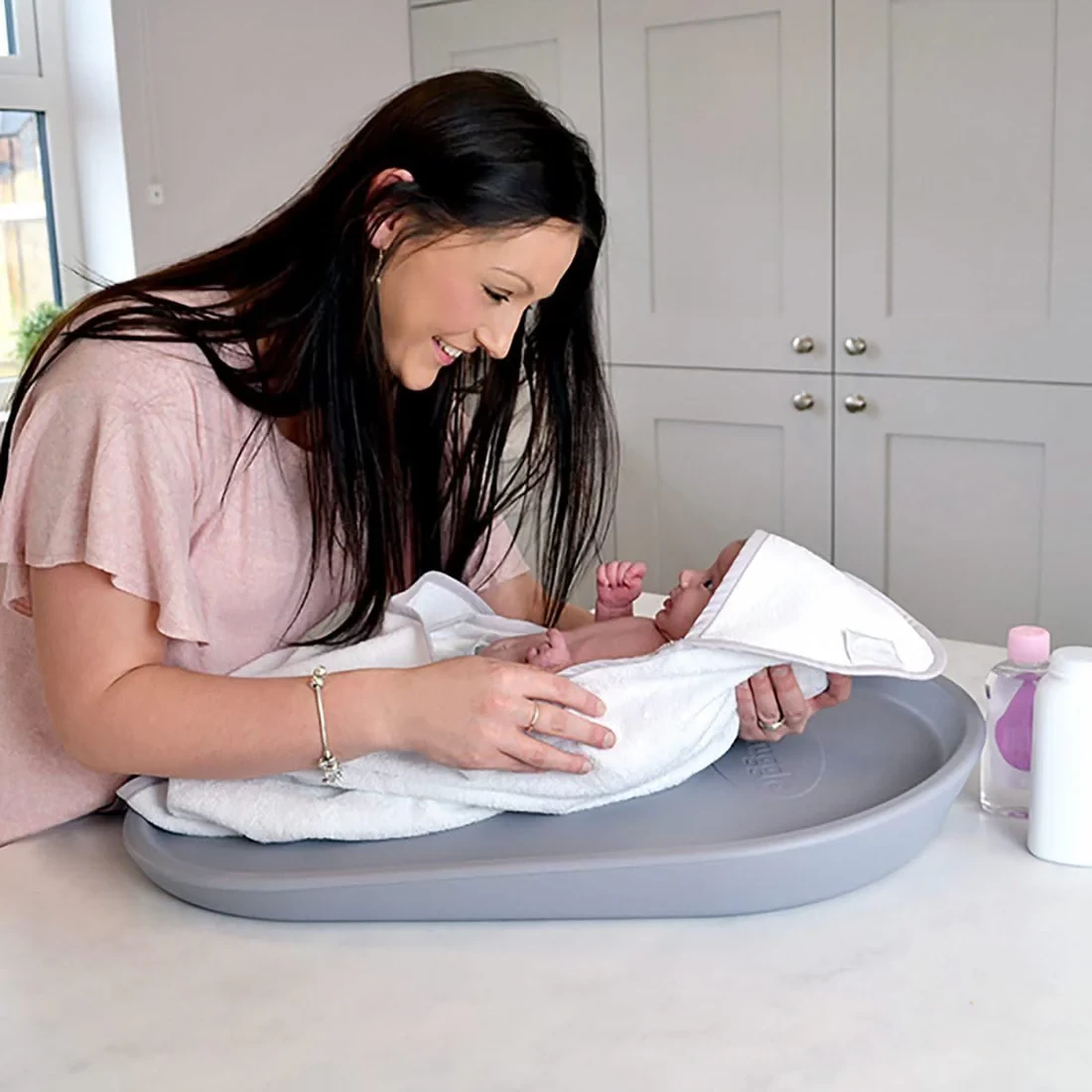 A mum with her newborn using the Shnuggle changing mat