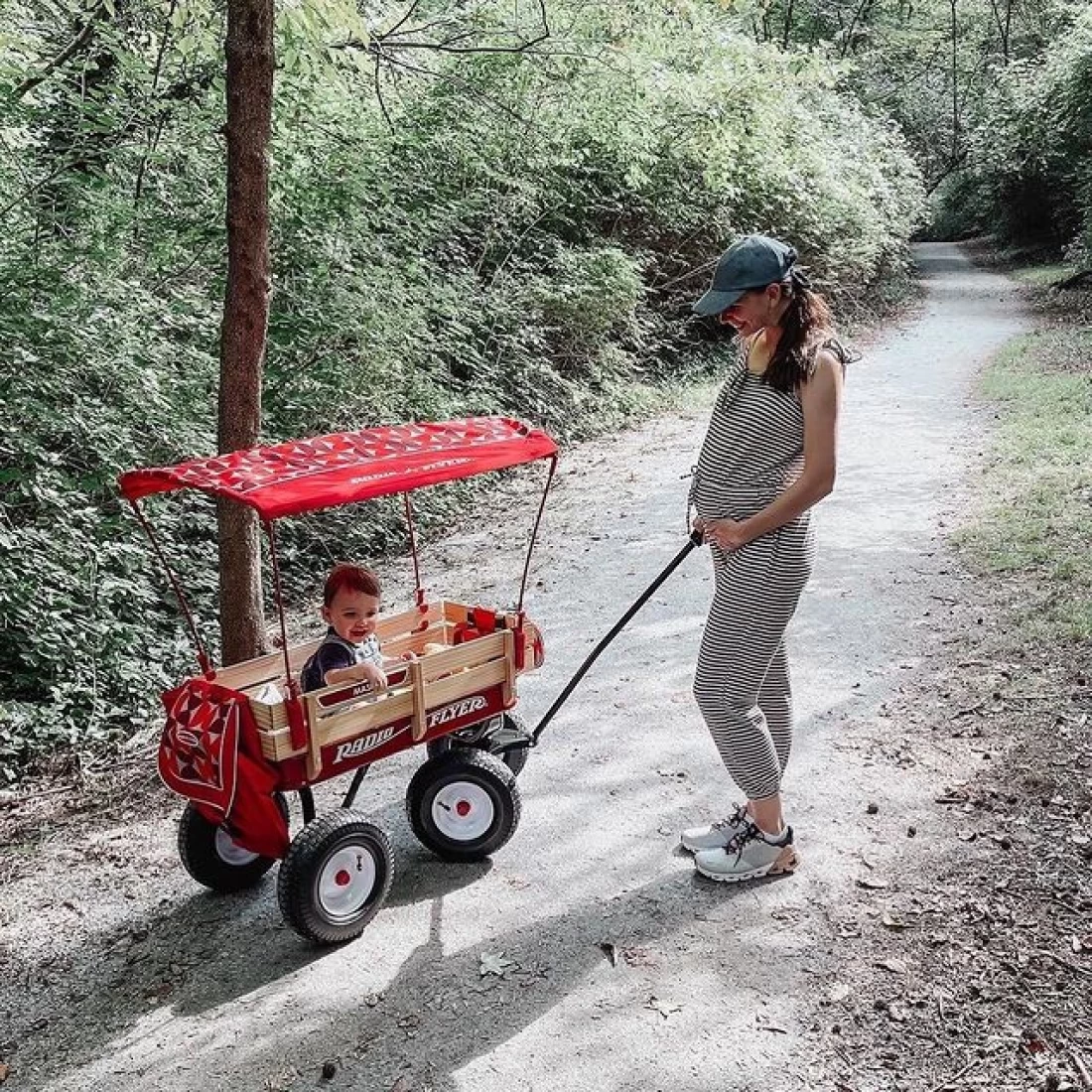 Pregnant mum with toddler riding in the best beach trolley full-size all-terrain steel and wood wagon.