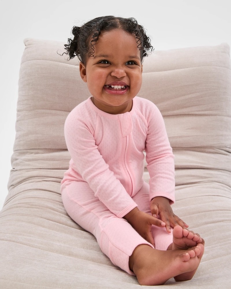 A baby girl in a target organic zip growsuit