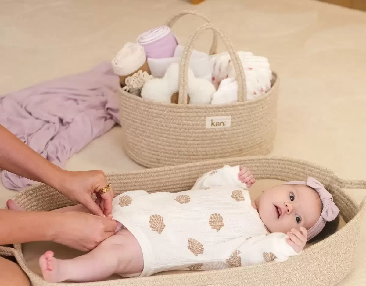 a baby on a change mat with a nappy caddy behind it