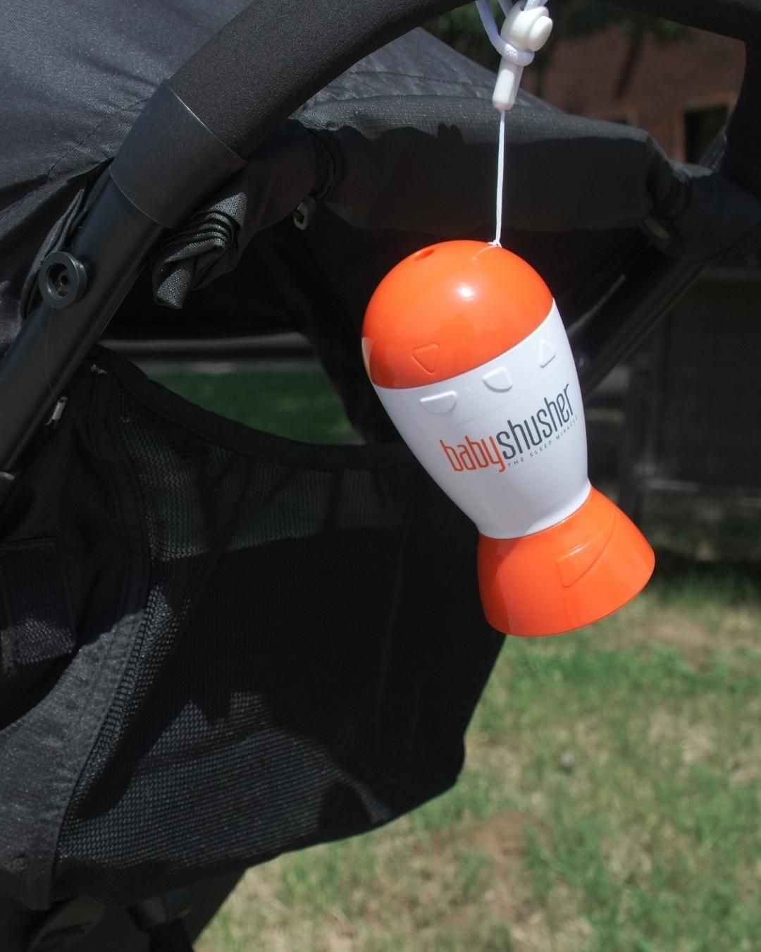 Portable baby shusher sleep aid white noise machine clipped to a bag for travel.