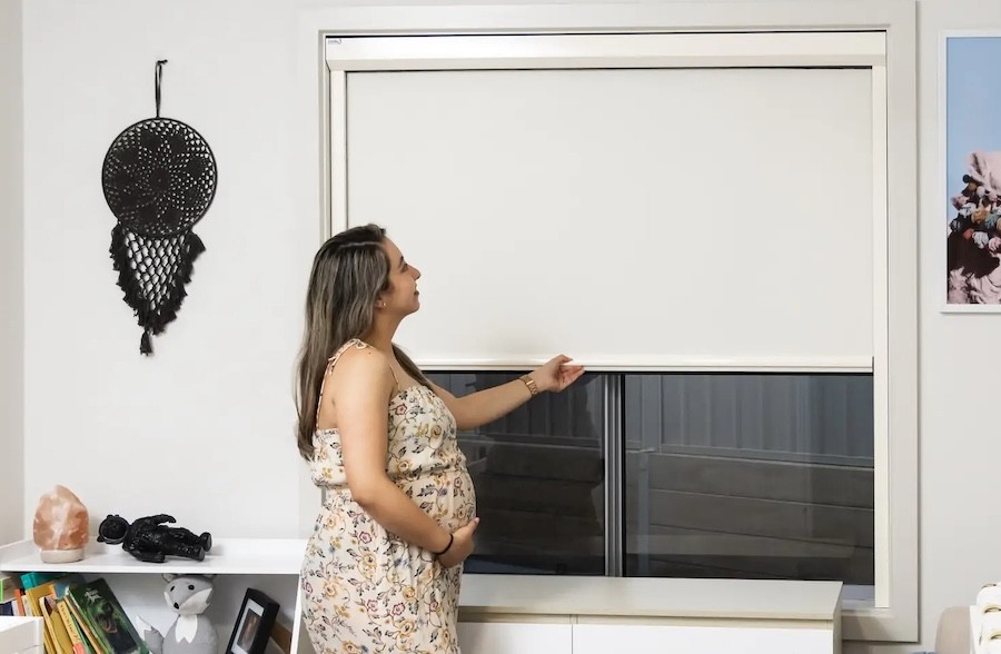 An Australian mother adjusting her retractable blackout blinds in a nursery
