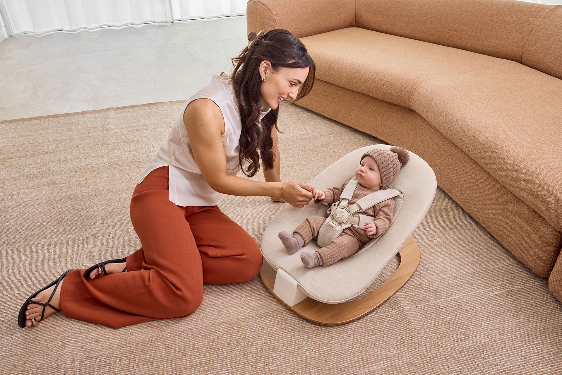 Mother leaning toward her baby lying on one of the best baby bouncers in Australia