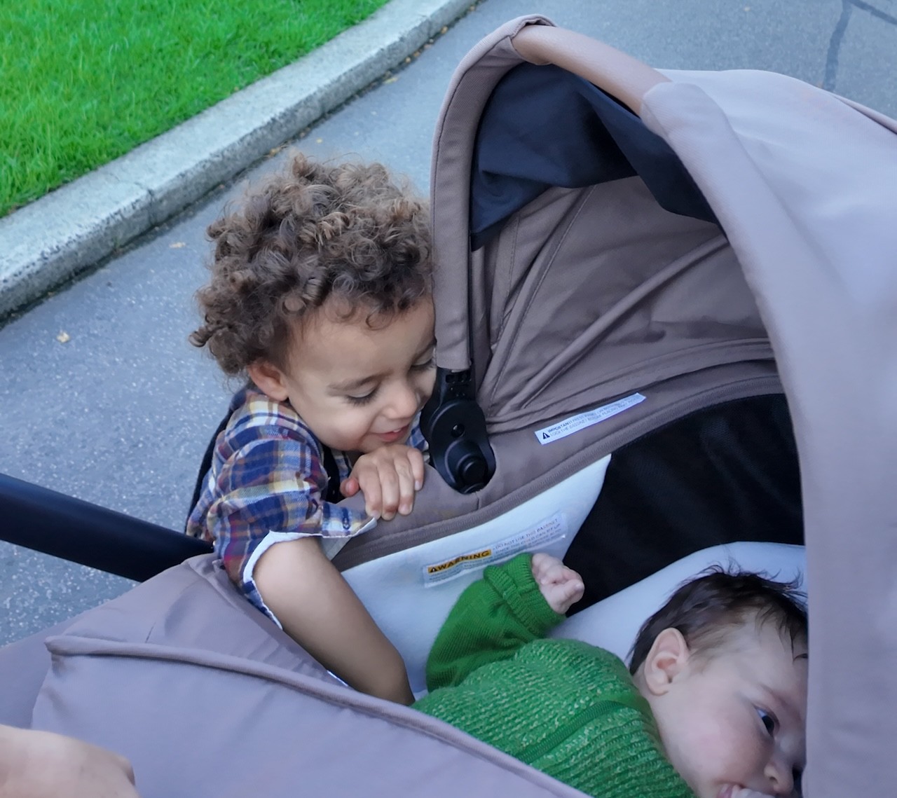 A toddler playing with his baby sibling in the Babybee Alto pram