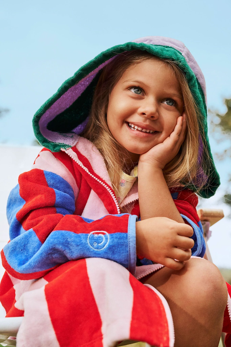 A girl smiling while wearing a hooded beach towel for kids