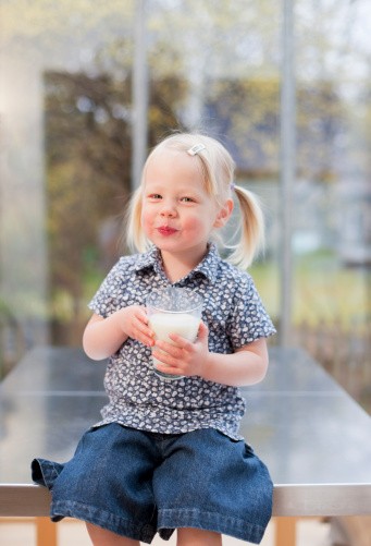 Smiling toddler sipping goat milk, illustrating the truth behind toddler goat milk myths