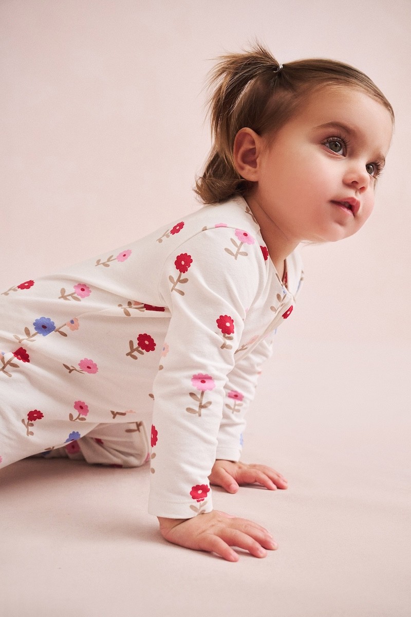 A baby girl wearing a floral cotton on zip growsuit