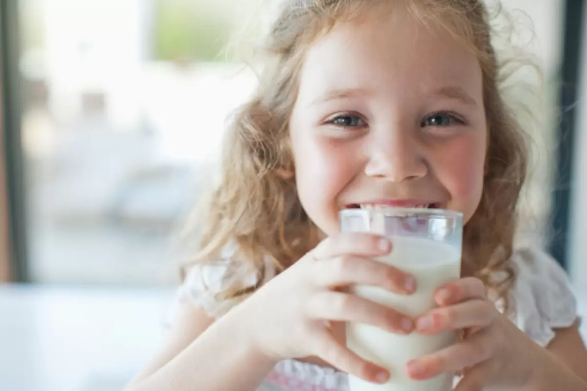 a blonde girl drinking a glass of Oli6 Goat Milk Formula milk