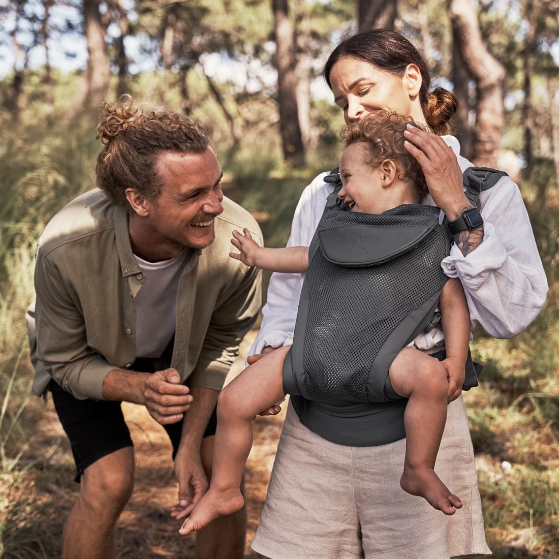 Happy family moment with mum using Redsbaby CONNECT Plus, the best baby carrier, and dad engaging baby in play.