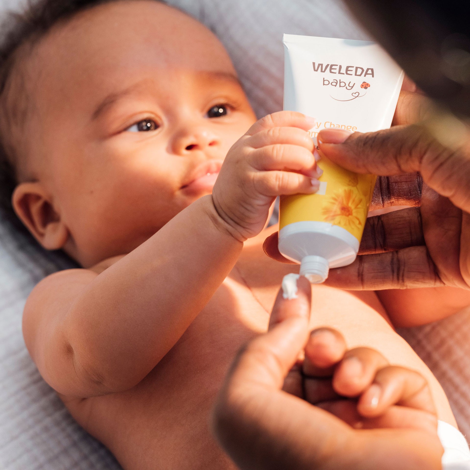 Gentle nappy care moment – mum using Weleda nappy change cream on baby after a warm bath.