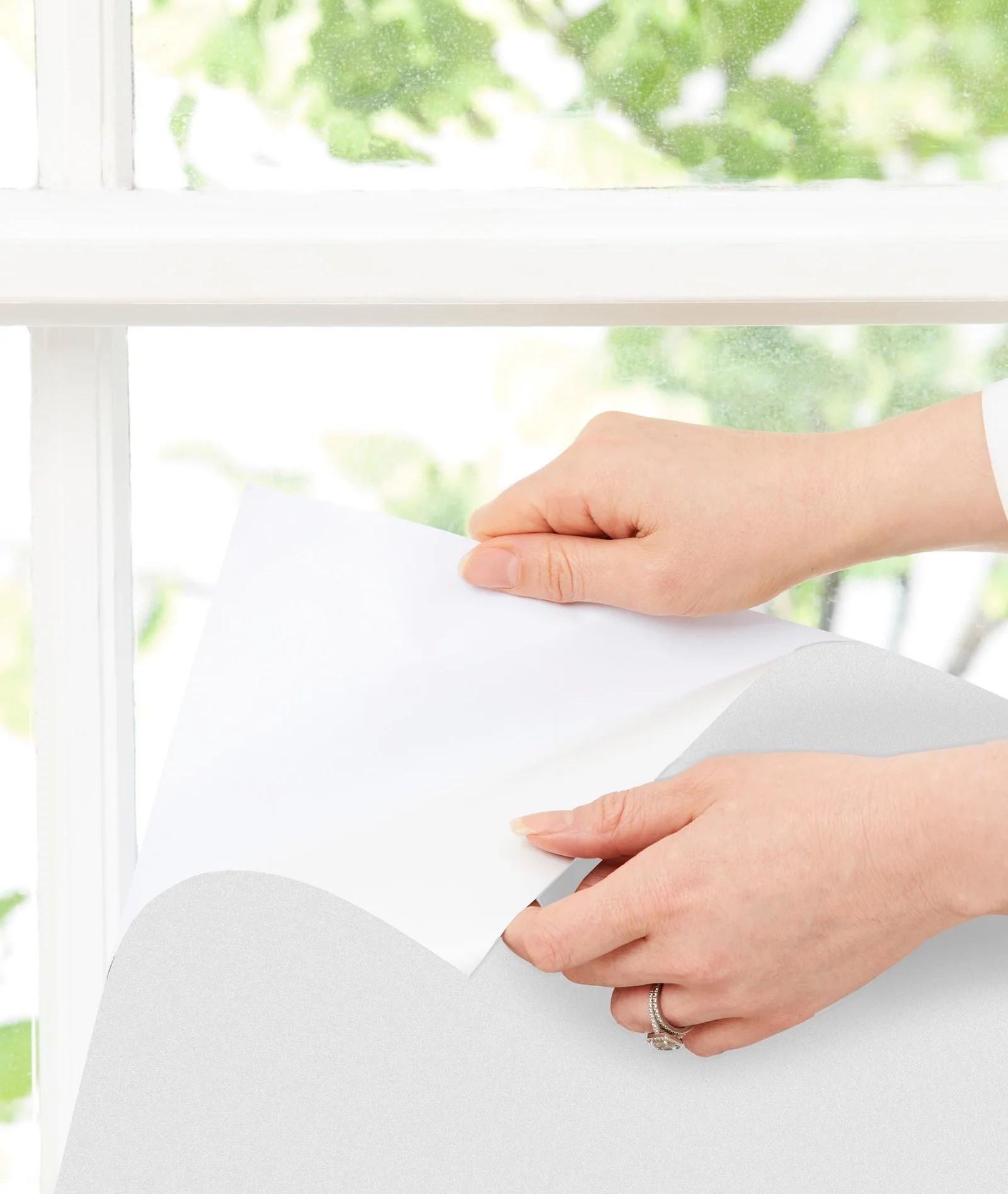 Hands peeling the ergopouch window blockout blinds to stick on