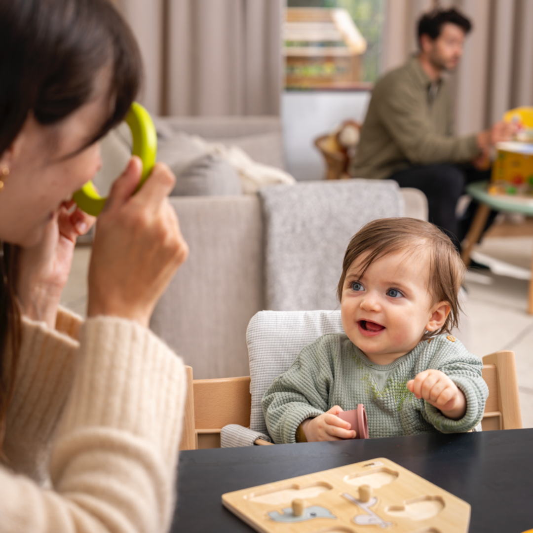 A warm, engaging mealtime scene with a mum feeding or interacting with her baby seated comfortably in the Tripp Trapp high chair.
