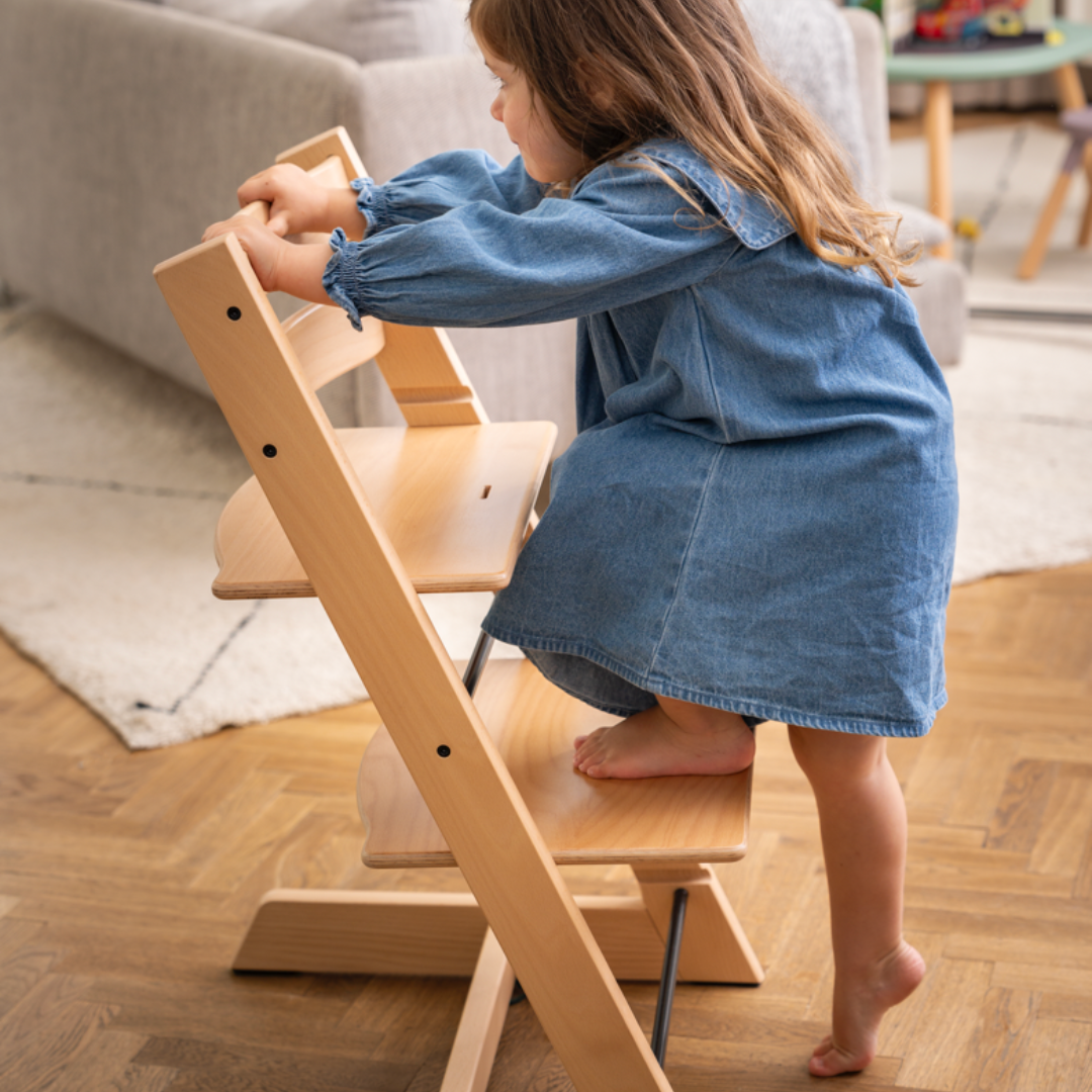 Toddler climbing onto Tripp Trapp, the best baby high chair designed for independence and safety.
