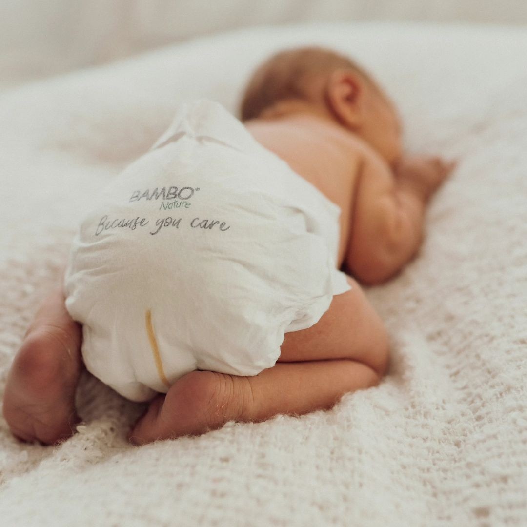 Baby sleeping peacefully on the bed wearing Bambo Nature Eco disposable nappies, known for gentle, eco-friendly comfort.