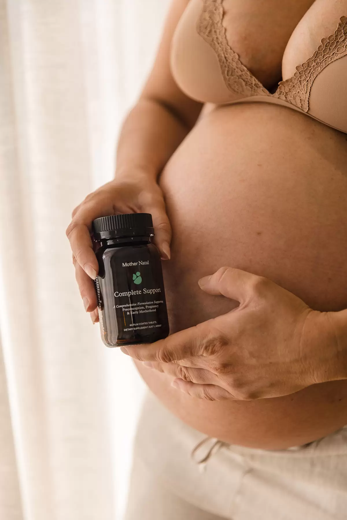 Pregnant woman holding Mother Natal supplement and showing baby bump – one of the best prenatal vitamins in Australia.