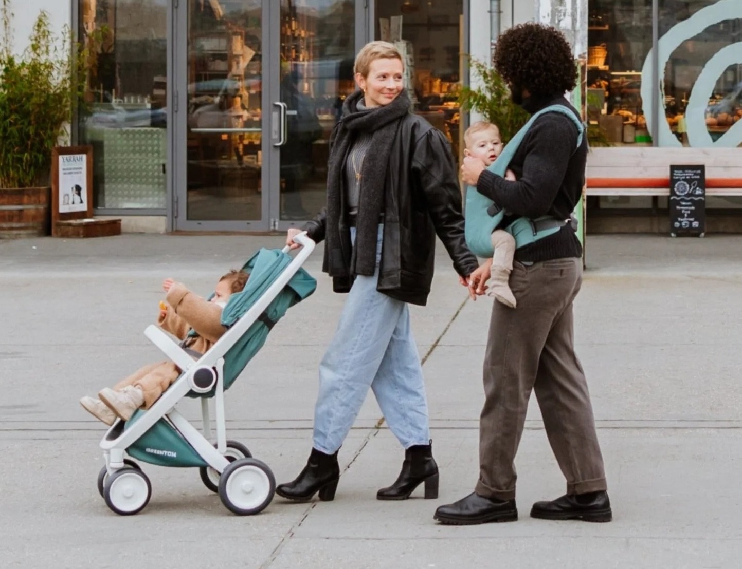 Two parents walking their child in the eco friendly baby pram by Greentom