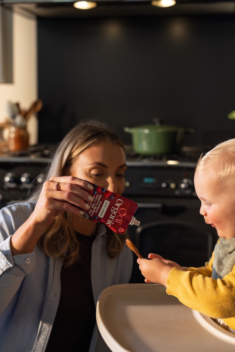 A mum giving her baby Odi baby food pouches on a spoon