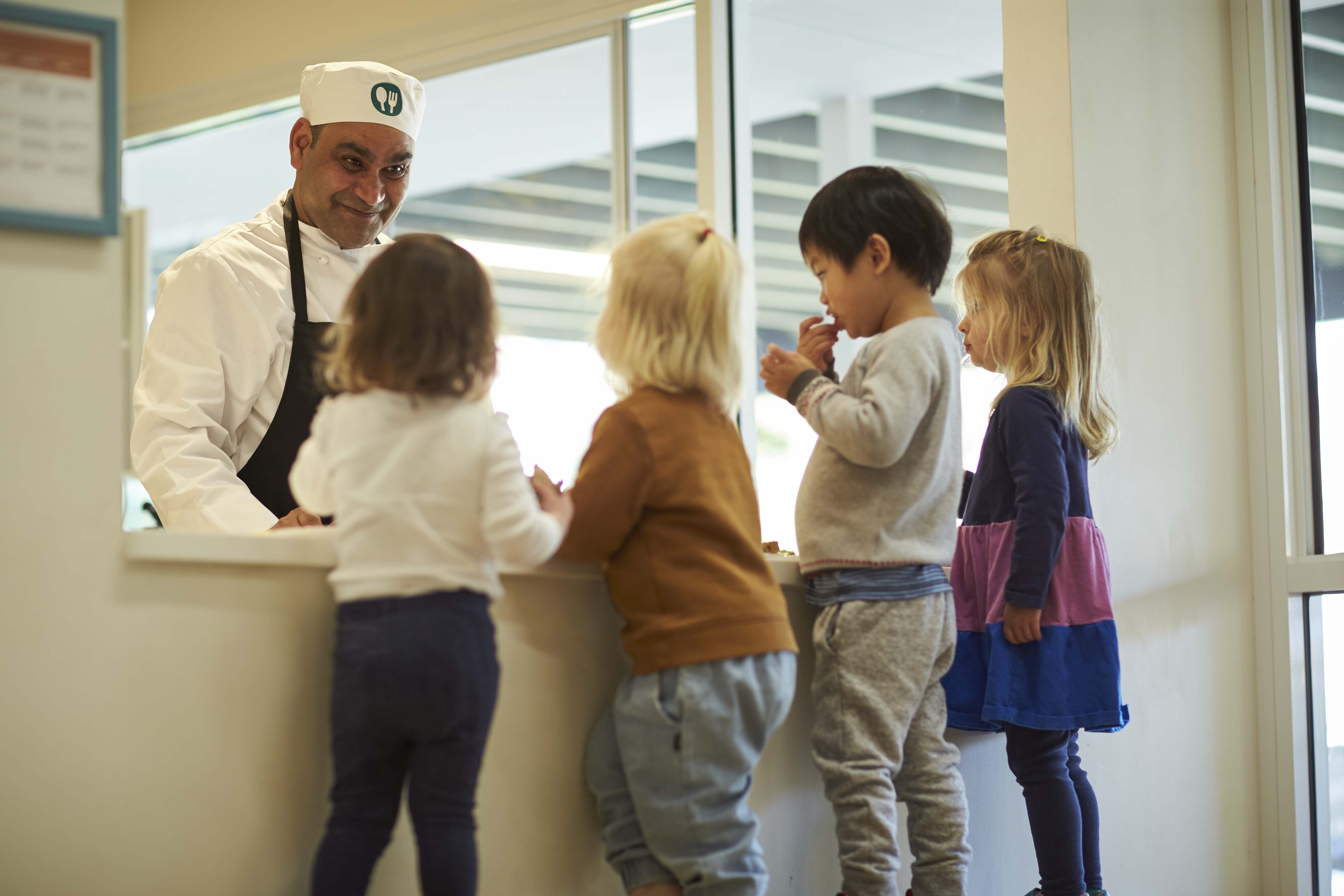 Chef serving children at one of the best childcare and daycare centres, showing healthy meal programs.
