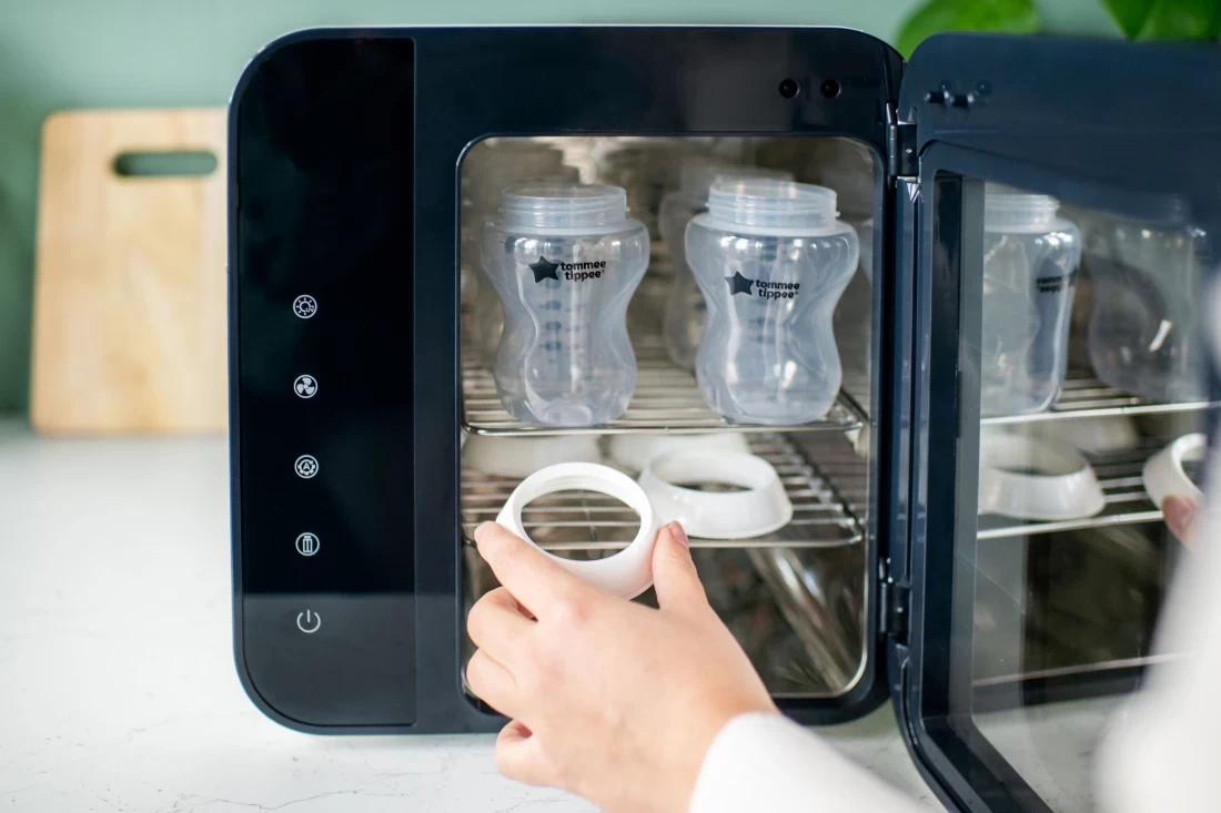 Australian mum loading a bottle into the Tommee Tippee Ultra UV 3-in-1 bottle steriliser and dryer, version 3, for hygienic baby feeding