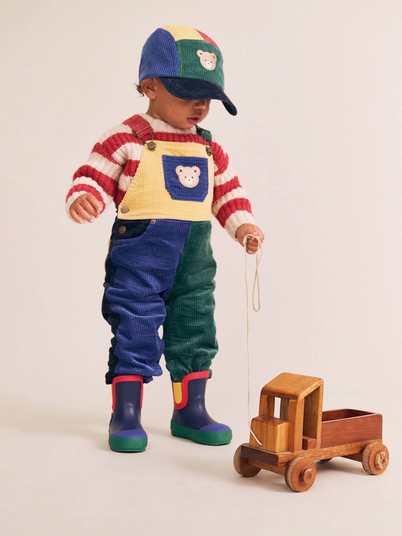 A baby wearing cord overalls by baby clothing brand huxbaby